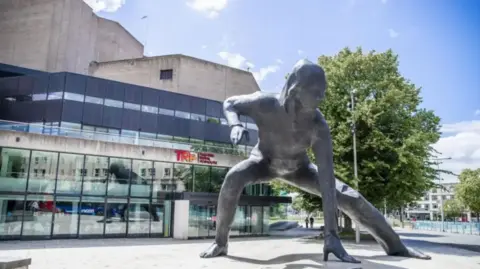 The exterior of Theatre Royal Plymouth. There is a grey statue standing outside.
