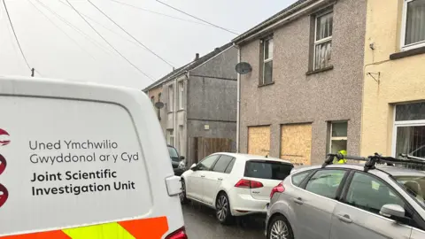 police officer standing outside boarded up house