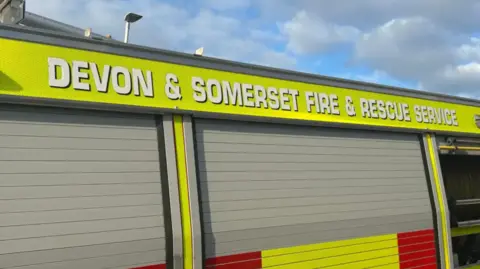 The side of a fire van with Devon & Somerset Fire & Rescue Service written at the top of the van.