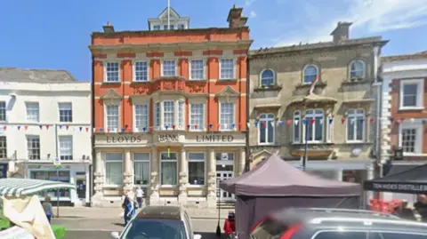 A building with pillars which says 'Lloyds Bank Limited' and cars parked in front of it in the centre of Devizes