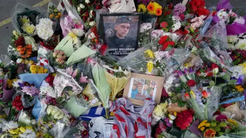 PA Media Flowers, frames, letters, and photos form a memorial for Harvey Willgoose.