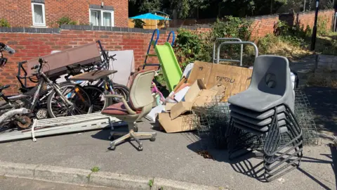 Chairs, a garden slide and cardboard among a pile of items ready for disposal on a street in Sheffield.