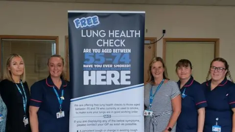 Nurses and staff at South Tyneside and Sunderland NHS Foundation Trust standing next to a banner advertising free lung health checks for those aged between 55 and 74.
