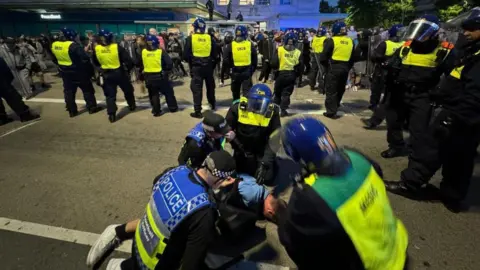 Getty Images Police officers detain individuals in Plymouth after they tried crossing into the anti-racism counter protest they tried crossing into the counter protest