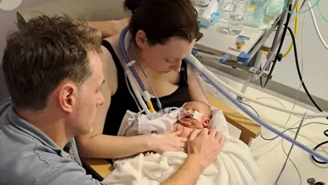 Mother and father holding onto their stillborn baby in hospital.