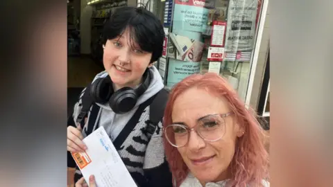 Family photo Finn Hall smiling wearing headphones holding a letter with his mum
