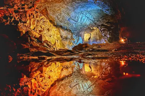John Harrison Inside the Devil's Arse (a cave), with the walls of the cave reflected in the water