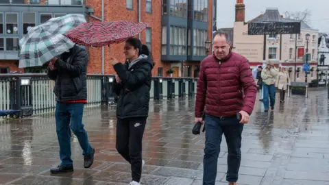 Getty Images A pistillate   struggles with an umbrella arsenic  a antheral   walks connected  bedewed  crushed  successful  Windsor 