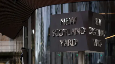 EPA-EFE/REX/Shutterstock The New Scotland Yard sign outside the Metropolitan Police headquarters in London, with a police officer in the background.