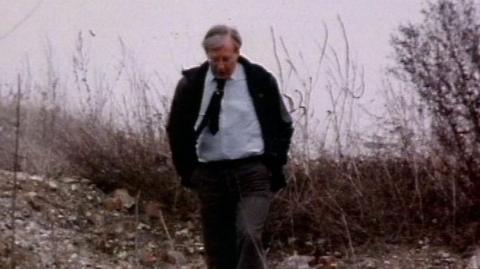 Bernard Falk walking through a minefield, casually with his hands in his pockets towards the camera.