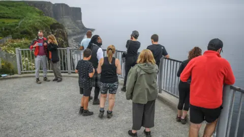 Getty Images A group of tourists gathered at a viewpoint at Kilt Rock on Skye.
