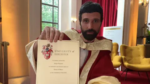 Pizzorno in a red gown holding a graduation certificate