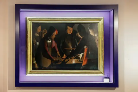 Stockton Borough Council The Dice Players hanging on the wall at Preston Park Museum, protected by a glass case with a purple frame.