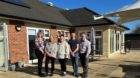 Five staff members - three woman and two men - pose outside the care home 