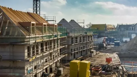 Scaffolding surrounds dozens of properties being built on an estate which has building paraphernalia scattered about as construction work is carried out