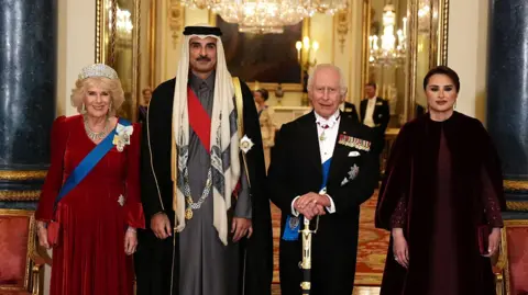 Reuters Queen Camilla, Qatari Emir Sheikh Tamim bin Hamad Al Thani, Queen Camilla, and the Qatari Emir's wife Sheikha Jawaher bint Hamad bin Suhaim Al Thani standing in fomral evening wear ahead of the state banquet, in Buckingham Palace