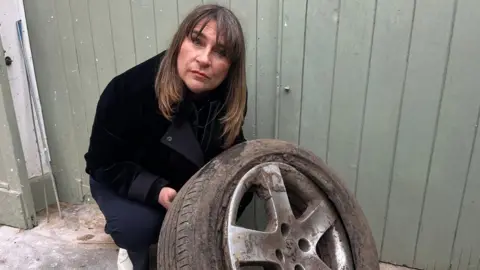 Sarah Gray holding a burst tyre