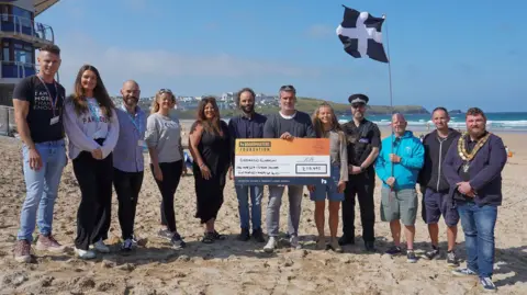 Boardmasters/Hugh Hastings The funding recipients on the beach with a large cheque