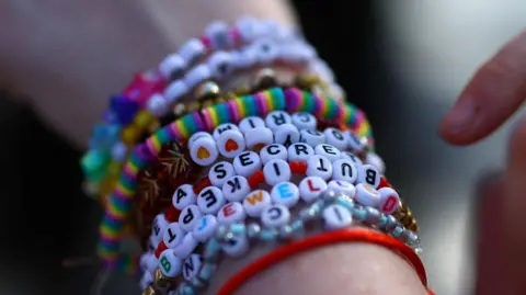 Reuters A person wearing homemade friendship bracelets with different Taylor Swift references