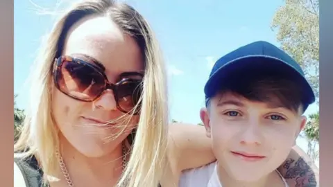 Leo Cavanagh A picture of Leo and his mum when they were younger. Leo is a small boy with brown hair and a blue cap on. His mum is blonde and wearing sunglasses and has her arm around Leo's shoulder. She has tattoos on her arm.
