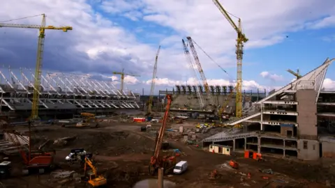 David Rogers/Allsport A view of the Millennium Stadium being built - there are three, half-finished stands around a large patch of mud that will become the pitch. Five different cranes are dotted around and there are various construction vehicles visible as well