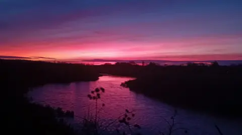 MR BEEBOOTS/WEATHERWATCHERS A purple and pink sky above a river in Chelmsford 