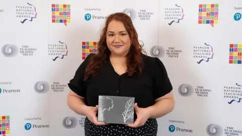 Pearson National Teaching Awards/Another Word Natalie with reddish-brown hair, a black top and black and white spotted skirt 