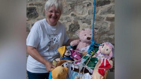 Jane Brown standing next to a basket of toys