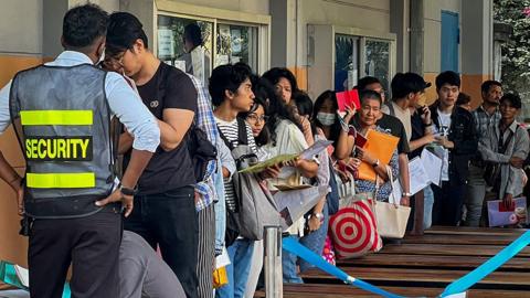 People queue to get visas in front of the embassy of Thailand in Yangon on February 16, 2024