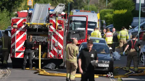 Fire engine and ambulance in a street with emergency service personnel in foreground 
