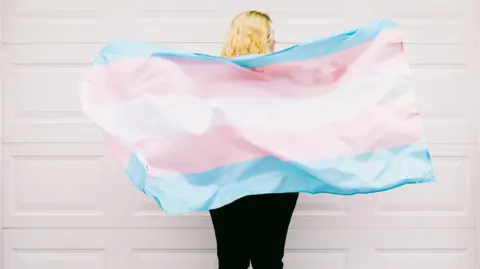 Getty A person holding a blue, pink and white flag. 