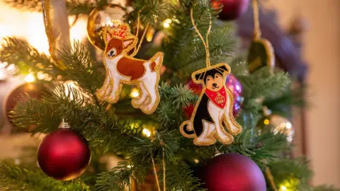 PA Media A Christmas tree decoration at Highgrove Gardens as staff prepare to welcome the public for Christmas celebrations in the Orchard Room, the estate's dedicated entertaining space. Two dogs are among the decorations alongside large red baubles