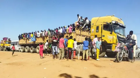 AFP People climbing on to a lorry to flee Wad Madani in Sudan - December 2023