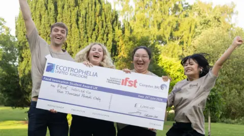 University of Reading A man and three women holding a giant cheque while jumping in the air to celebrate