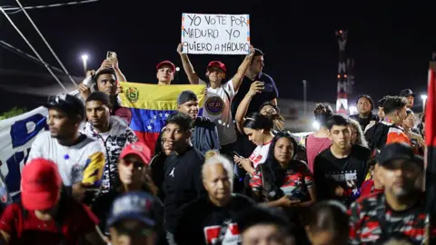 Jesus Vargas/Getty Images A woman holds a sign that reads, I VOTED FOR MADURO, I LOVE MADURO. during a protest to demand the release of Nicolas Maduro and his wife Cilia Flores on January 20, 2026 in La Guaira, Venezuela