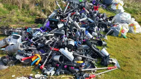 A heap of discarded vacuums on a hillside.