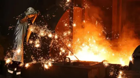 Getty Images: Sparks fly as a worker takes a sample of molten iron flowing from a blast furnace in Duisburg.