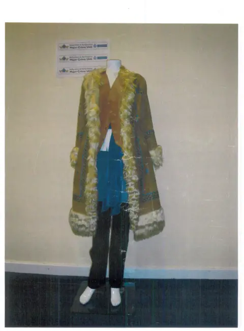 LOCATE INTERNATIONAL A mannequin wearing a brown Afghan coat, brown leather waistcoat, white cotton blouse, white cotton smock with a floral pattern and imitation lace, black jeans and a chiffon lace scarf.