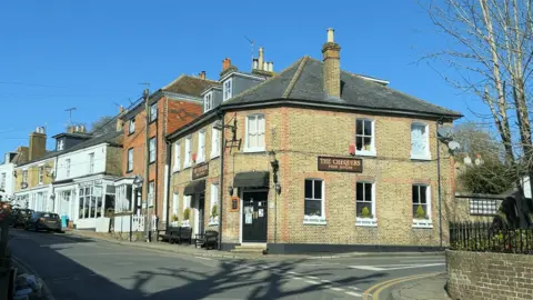 Piers Hopkirk/BBC A pub on corner with The Chequers written on the side.