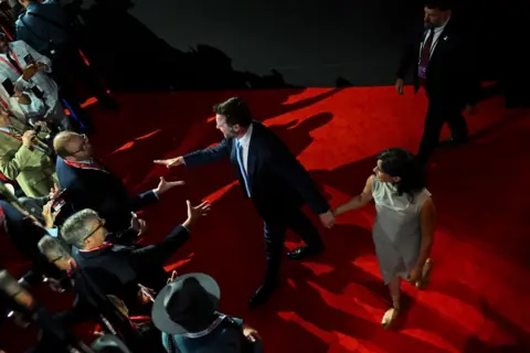 Getty Images Overhead changeable  of reporters trying to talk  to JD and Usha Vance connected  reddish  carpet