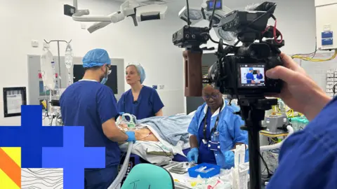 BBC A BBC camera man is filming at an operating theatre at the Royal Free Hospital , filming complex cancer surgery taking place 