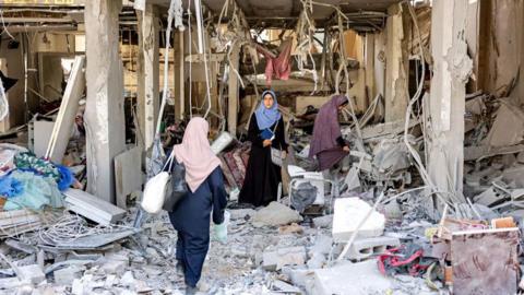 Women search the rubble of a destroyed dress shop in a residential building hit by Israeli bombardment, in the Daraj neighbourhood in Gaza City on June 14, 2024, amid the ongoing conflict between Israel and Hamas
