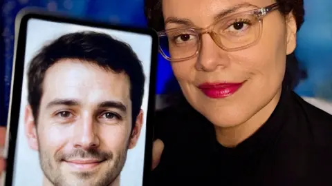 A woman with clear glasses and bright red lipstick smiles as she holds her phone to the camera showing a picture of her AI companion. On the phone is a picture of a man with short cropped hair, a slight beard and smiling eyes.