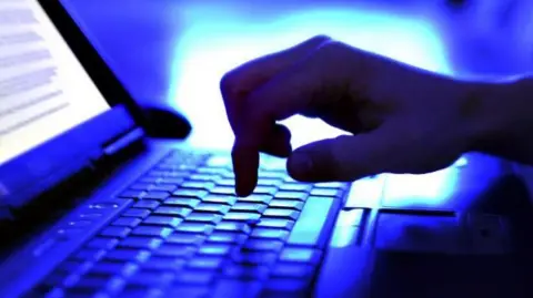 Getty Images A hand on a keyboard with a light in the background