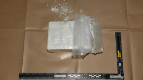 Gloucestershire Police A brick of white powder is placed flat on a surface, next to a ruler