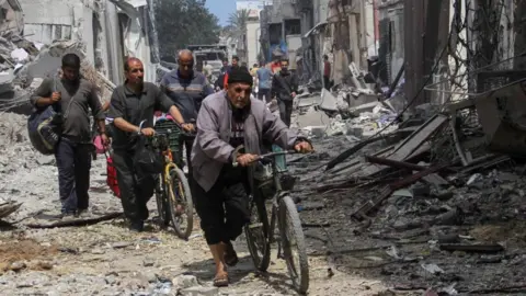Palestinians walk through rubble in Zeitoun neighbourhood, Gaza City