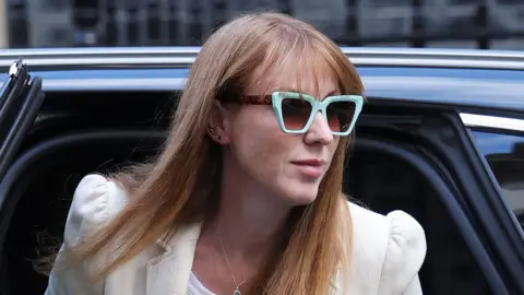 Angela Rayner, wearing bold green sunglasses, stepping out of a car at Downing Street