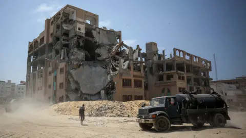 Reuters A truck in front of a building in ruins.