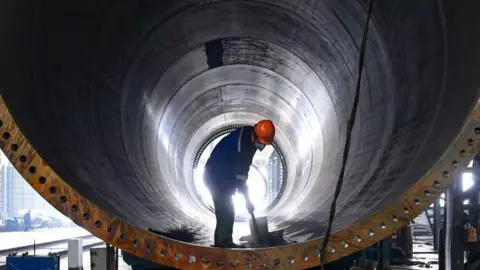 Um trabalhador trabalha em uma fábrica que fabrica equipamentos de energia eólica em Weinan, condado de Baishui, China, em 16 de outubro de 2024, na Getty Images.