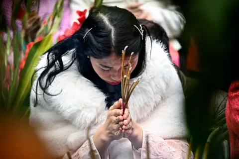 Nhac Nguyen/AFP A woman prays  while holding incense